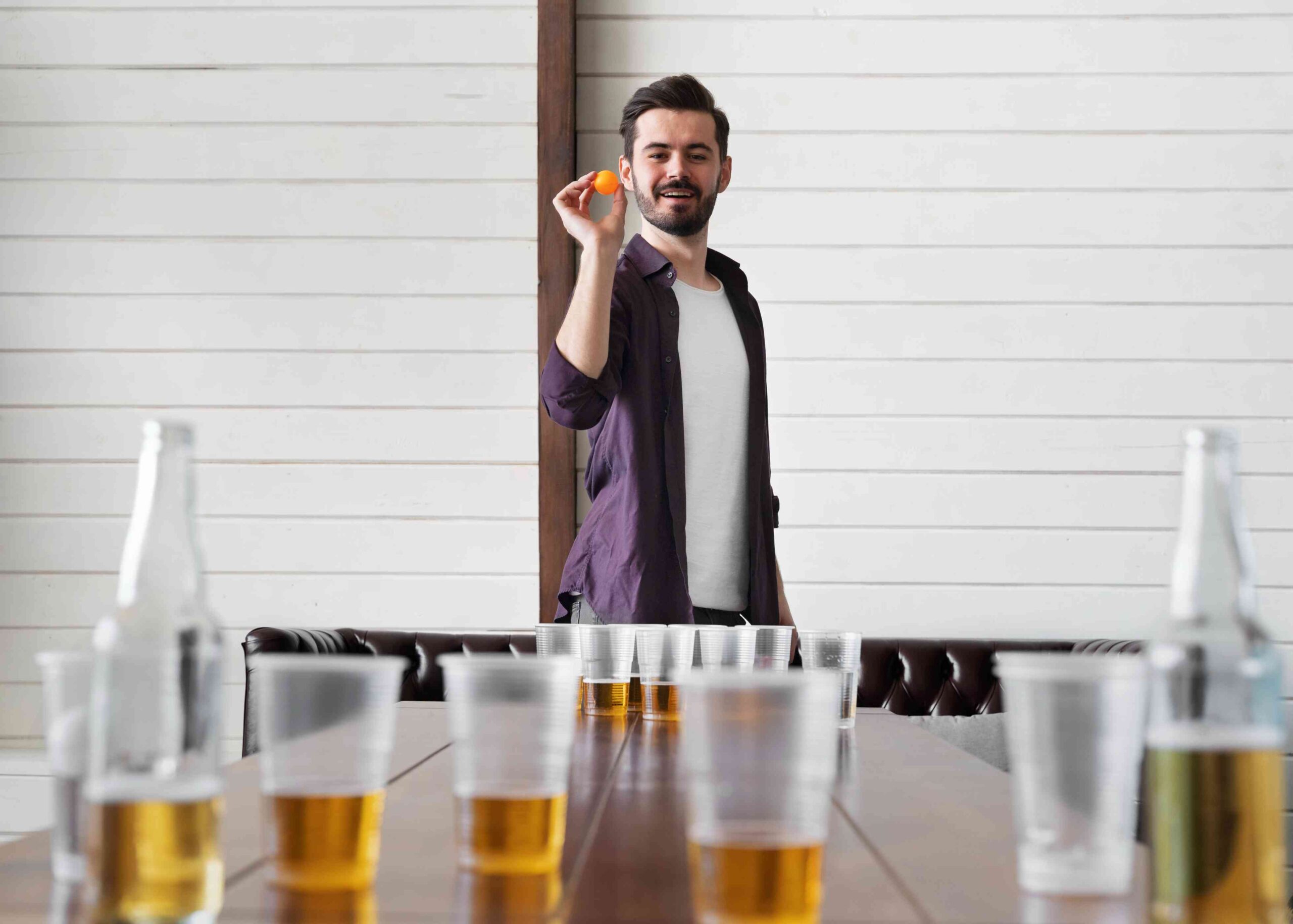 Man playing beer pong indoor party 1 scaled